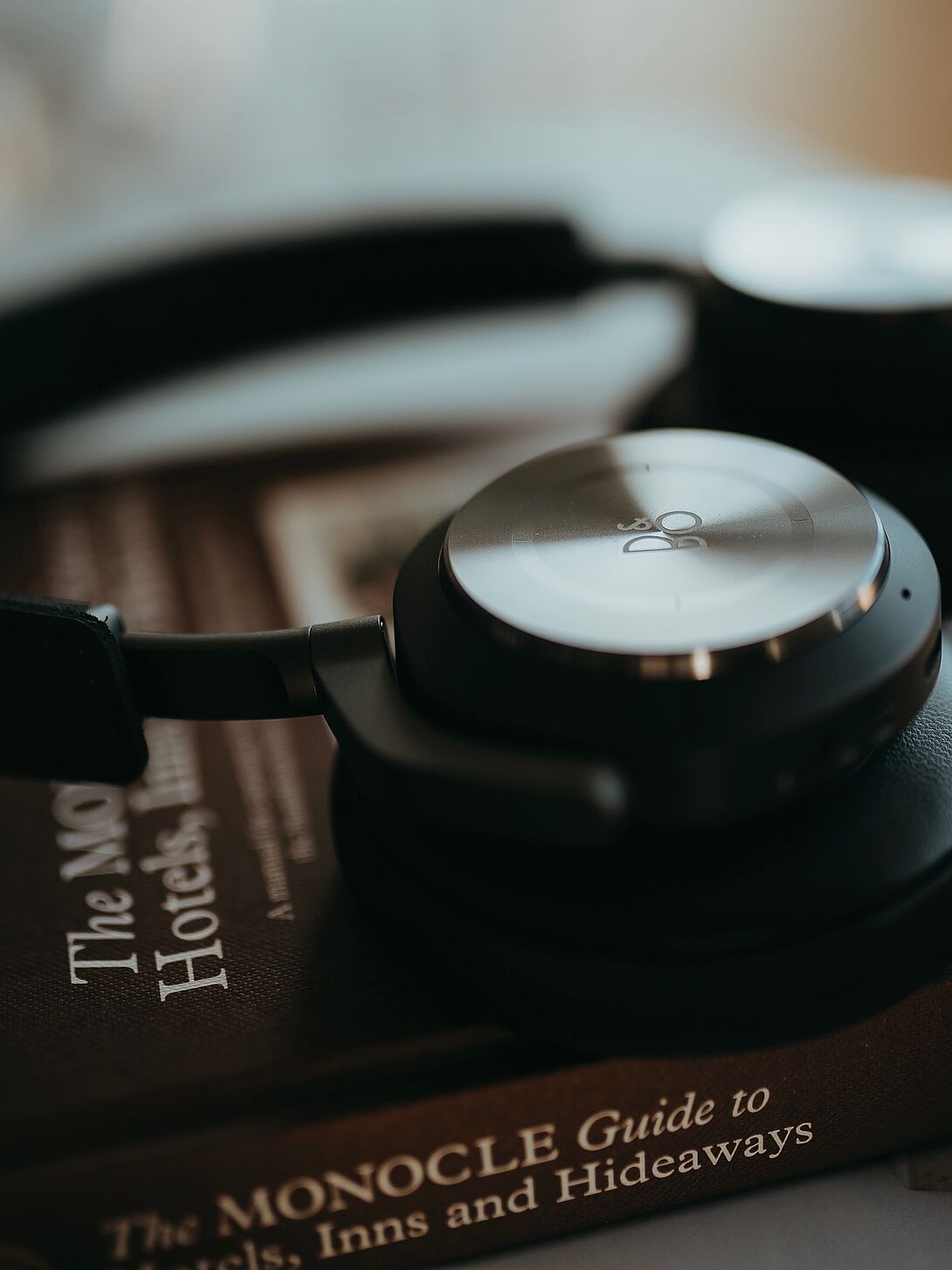 Close-up of black over-ear headphones resting on a book, with soft depth of field and subtle color overlay.
